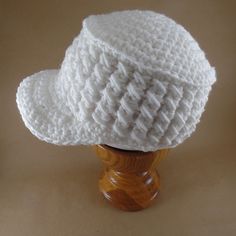 a white crocheted hat sitting on top of a wooden stand