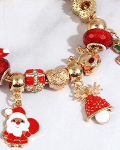 a red and gold christmas charm bracelet with santa clause charms on it's side