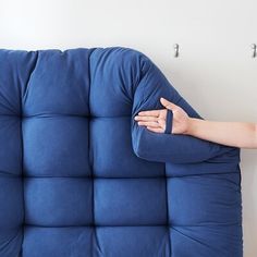 a person with their hand on the back of a blue couch