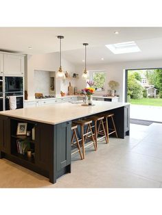 a large kitchen with an island and bar stools next to it, in front of a sliding glass door