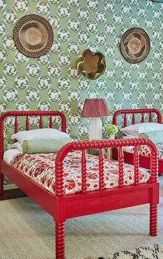 two red beds in a room with green wallpaper