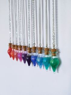 six necklaces with different colored sand in them hanging on a white wall next to each other