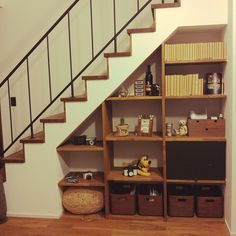 a book shelf under the stairs with baskets and books