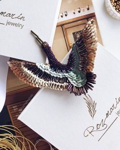 a bird brooch sitting on top of a piece of paper next to other items