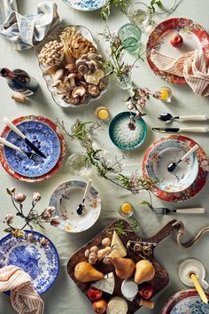 a table topped with plates and bowls filled with different types of food next to utensils