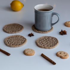 a cup of tea next to some cookies and cinnamon sticks