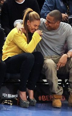 a man and woman sitting next to each other on a bench at a basketball game