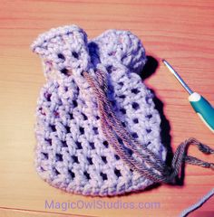 a crocheted bag sitting on top of a wooden table next to a knitting needle