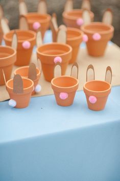 many clay pots are lined up on a table with paper bunny ears and pink pom - poms