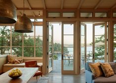 a living room filled with furniture and lots of glass doors leading to an outside deck