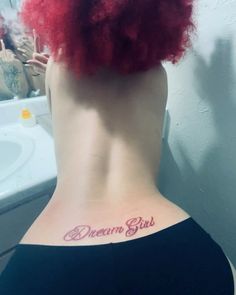 a woman with red hair has her back tattoo