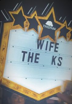 a sign that says wife the k's with stars above it and people standing around