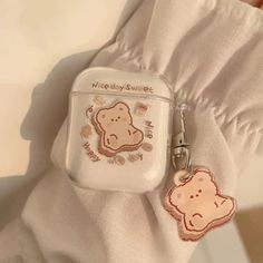 a white case with a brown teddy bear on it and a keychain attached to it