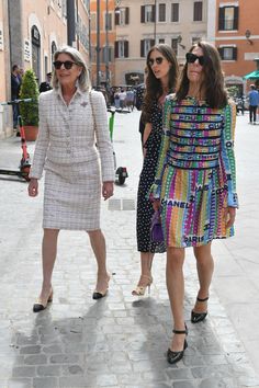 three women walking down the street in dresses and heels, with one woman wearing sunglasses