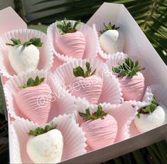 a box filled with chocolate covered strawberries on top of a table next to palm leaves