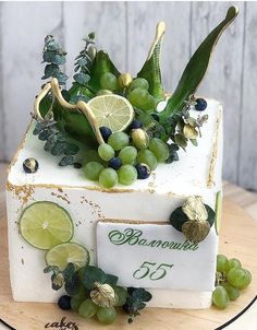 a cake decorated with grapes, limes and leaves