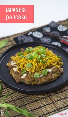 a black plate topped with food on top of a bamboo tablecloth next to chopsticks