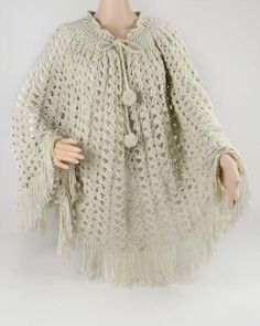 a mannequin wearing a white crocheted ponchy with tassels