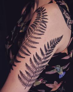 a woman's arm with a black fern tattoo on it