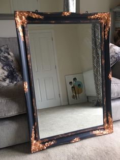 a mirror sitting on top of a couch in front of a door and a chair