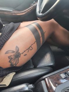 a woman with tattoos on her arm sitting in a car