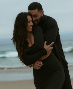 a man and woman hugging on the beach