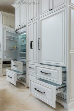 a kitchen with white cupboards and drawers in it's center, including an open refrigerator