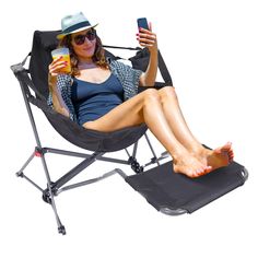 a woman sitting in a chair with her legs crossed and holding a drink while looking at her cell phone