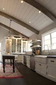 a large kitchen with white cabinets and wood beams on the ceiling is pictured in this image