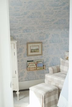 a bedroom with blue and white wallpaper, a chair and ottoman in the corner