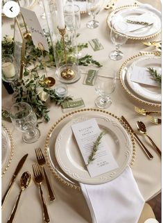 the table is set with white plates and silverware, gold rimmed cutlery