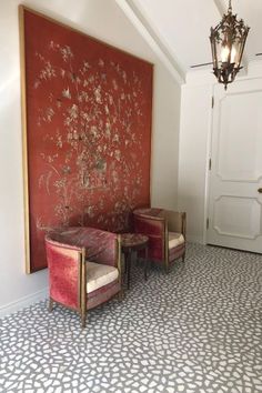 two red chairs sitting next to each other in front of a painting on the wall