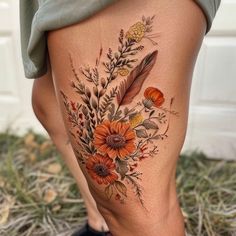 a woman's thigh with flowers and feathers on it