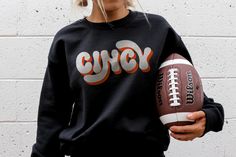 Cincy Crewneck, Cincinnati Bengals Vintage Vibes Crewneck Introducing the Cincy Crewneck, a must-have for any proud Cincy resident or fan! Embodying the charm of Cincinnati, this retro-inspired script Cincy sweatshirt brings a nostalgic vibe to your everyday style. Perfect for Bengals fans, or anyone who loves to show off their hometown pride. Whether you're strolling through the Queen City or simply want to show off your love for all things Cincy, this sweatshirt will keep you warm and stylish all year round. Stand out with a touch of vintage flair and grab your very own Cincy Crewneck today! PRODUCT DETAILS: .: 50% cotton, 50% polyester .: Medium-heavy fabric .: Loose fit .: Runs true to size *All products are made to order. Colors may vary slightly from one computer/phone to another. CA Retro Game Day Sweatshirt With Letter Print, Hometown Pride, Queen City, Cincinnati Bengals, Vintage Vibes, Everyday Style, Retro Inspired, The Queen, Cincinnati