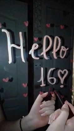 two hands holding scissors in front of a sign that says hello 16 and has hearts on it