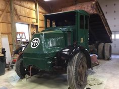 an old green truck parked in a garage