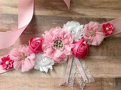 pink and white flowers are on the side of a wooden wall with ribbons around them