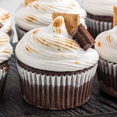 several cupcakes with white frosting and chocolate chips on top are sitting on a table