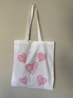 a tote bag with hearts drawn on it hanging from a hook in a wall