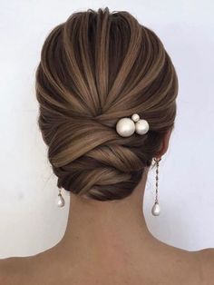 a woman with her hair in a low bun and two pearls on the back of her head