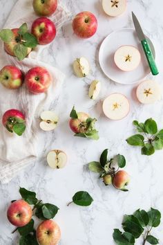 apples and leaves on a marble table with a knife