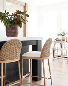 two wicker bar stools next to a counter with a potted plant on it