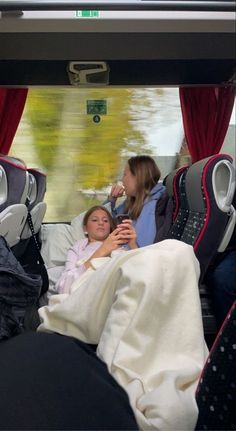 two women sitting on a bus with their feet up