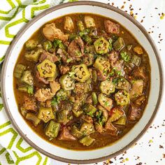 a white bowl filled with meat and vegetable stew on top of a green table cloth