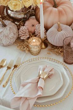 a table set with white plates and gold place settings