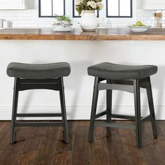 two stools sitting in front of a counter with flowers and plates on the table