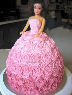 a cake that looks like a barbie doll in a pink dress with roses on it