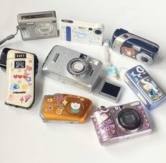 several different types of cameras sitting next to each other on a white surface with one camera open and the other closed