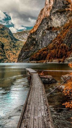 a wooden dock sitting on top of a lake surrounded by mountains