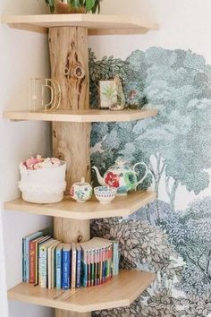 three wooden shelves with books and vases on them in front of a wall mural